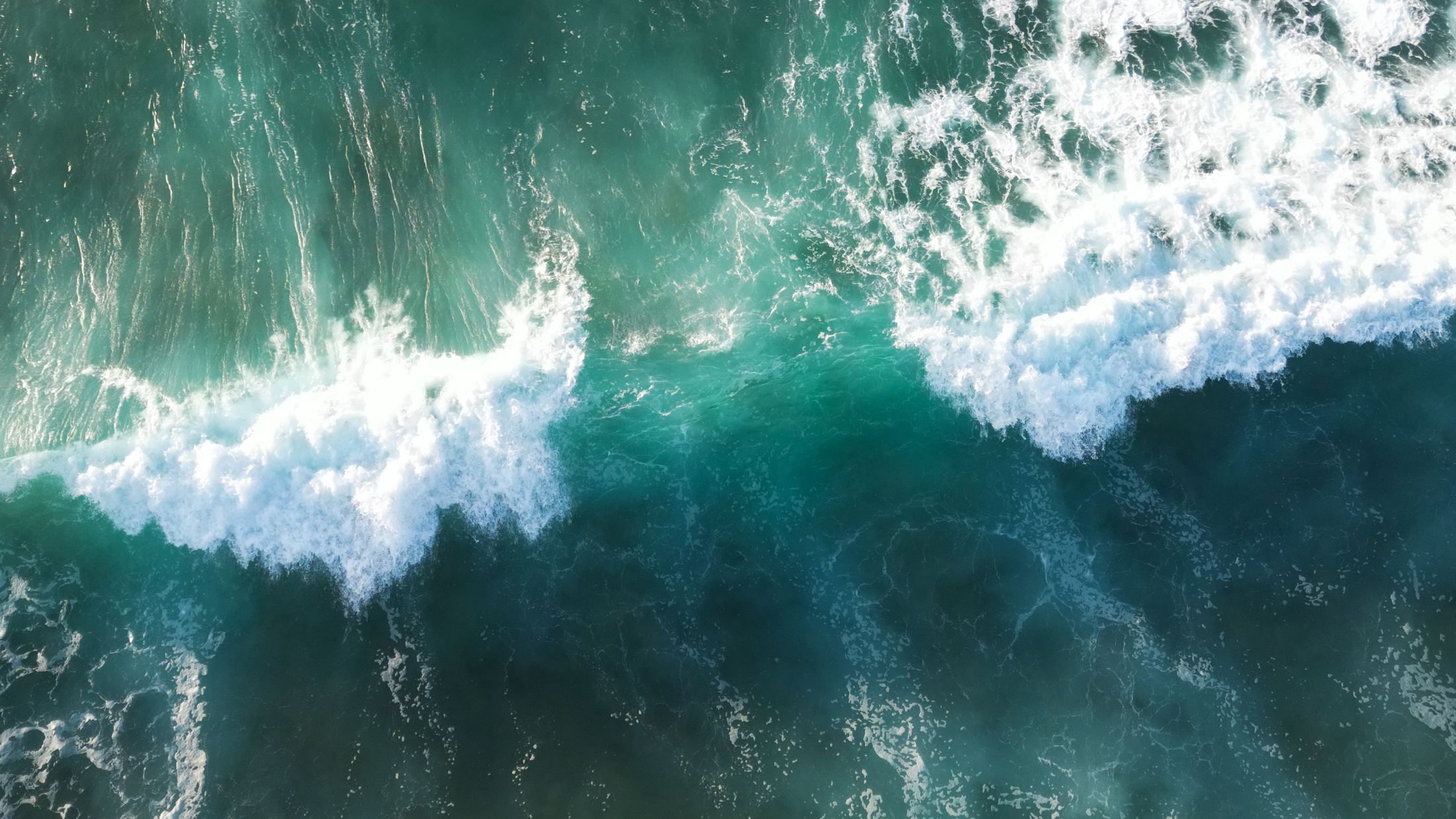 Aerial view of turquoise waves breaking into white foam