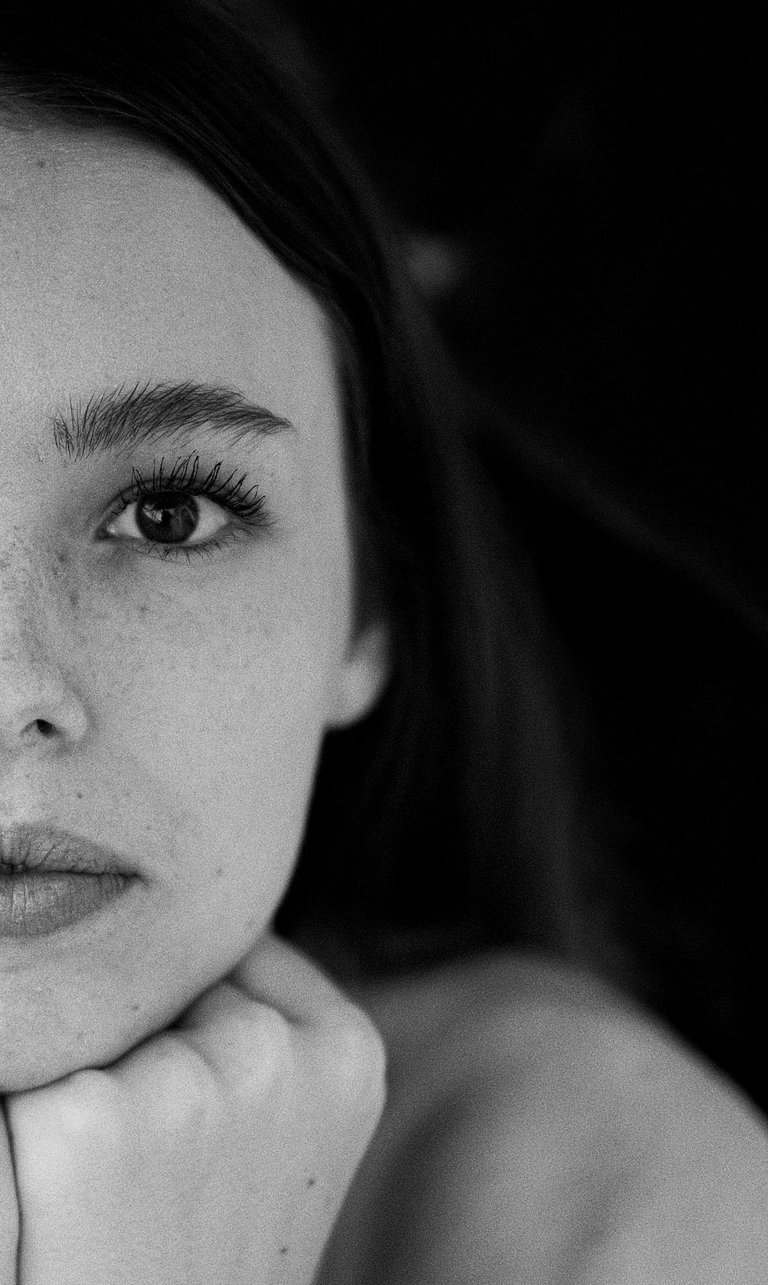 Black and white close-up of half a woman's face, chin resting on her hand