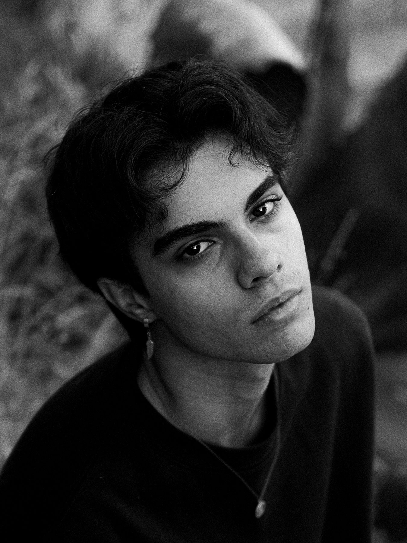 Black and white portrait of a young man with dark curls and a drop earring