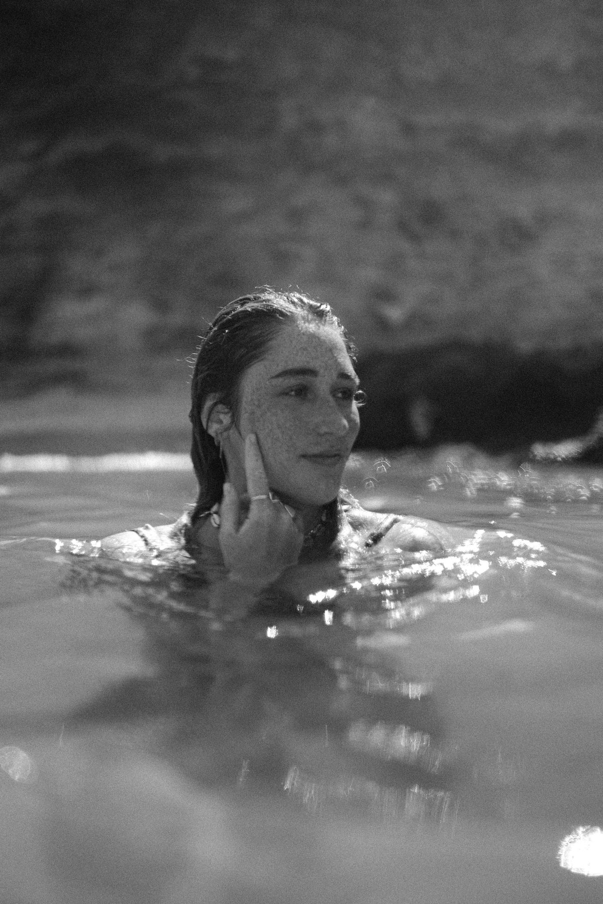 Black and white shot of a woman in the water touching her face