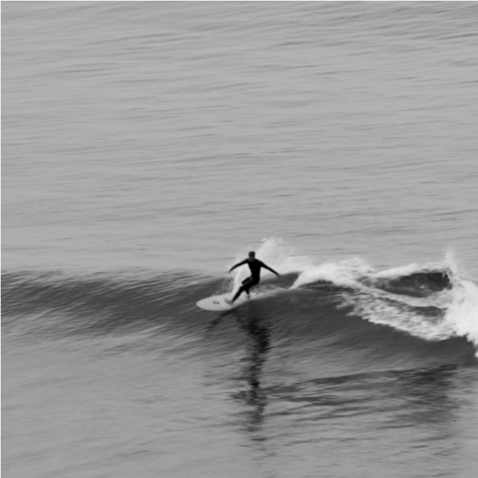 Surfer riding a small wave, black and white