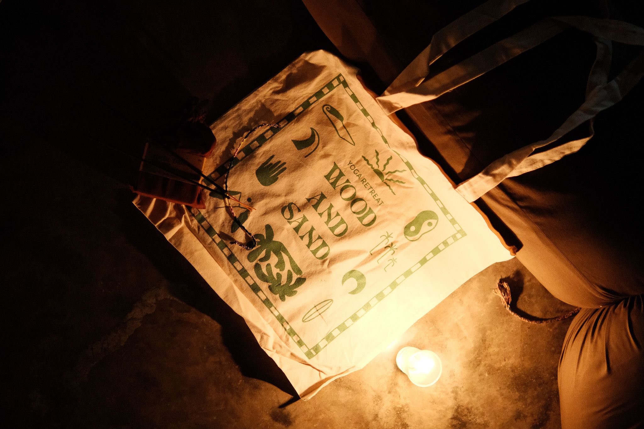 Wood and Sand tote bag lit by a candle on a dark floor