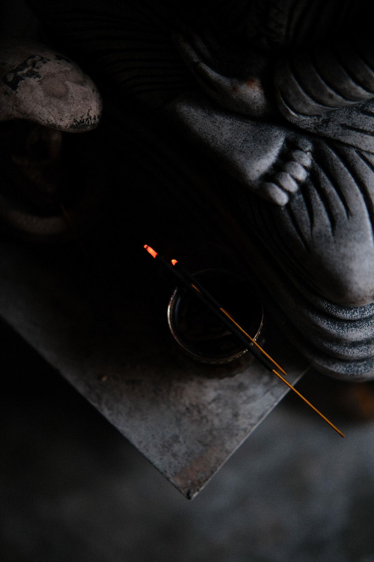 Incense smoking in front of a dark stone sculpture
