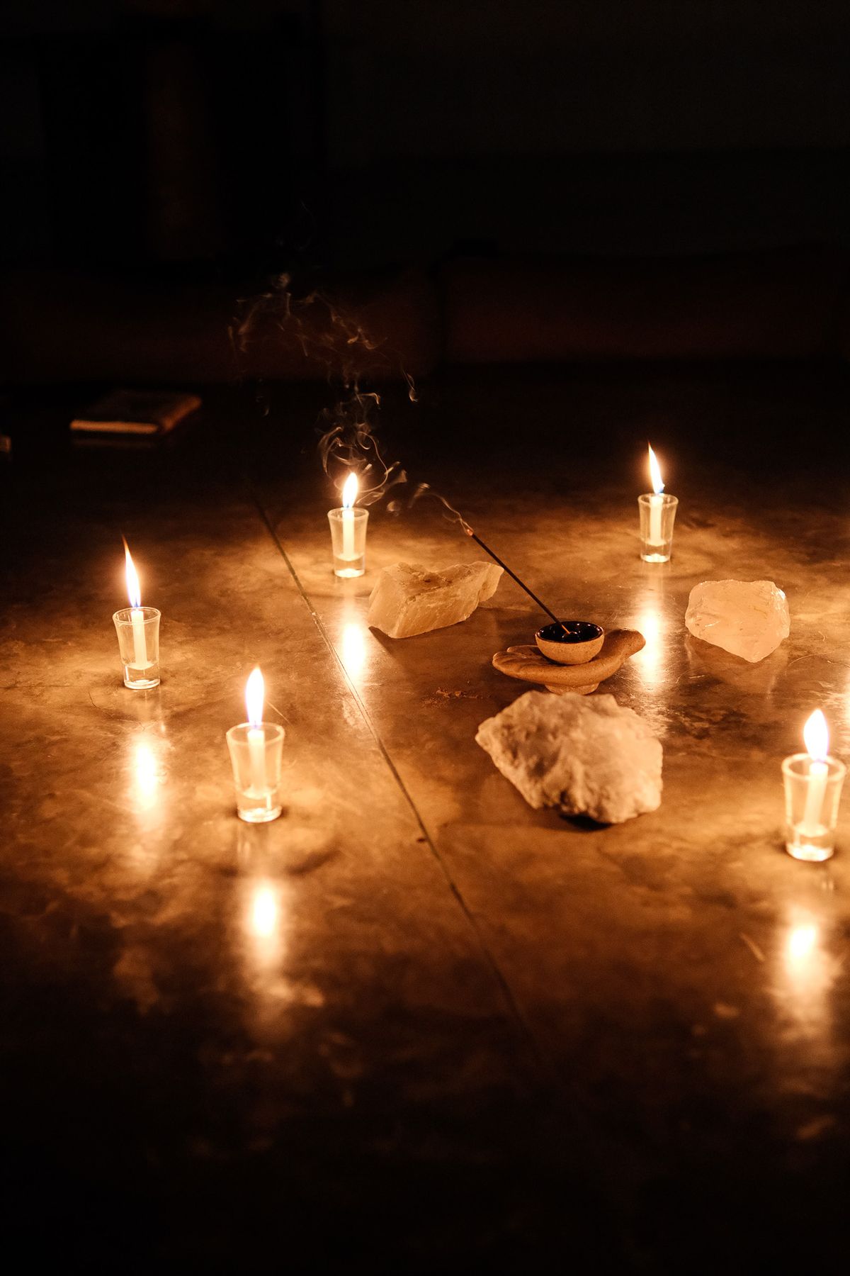 Candles, crystals and incense on the floor in the dark