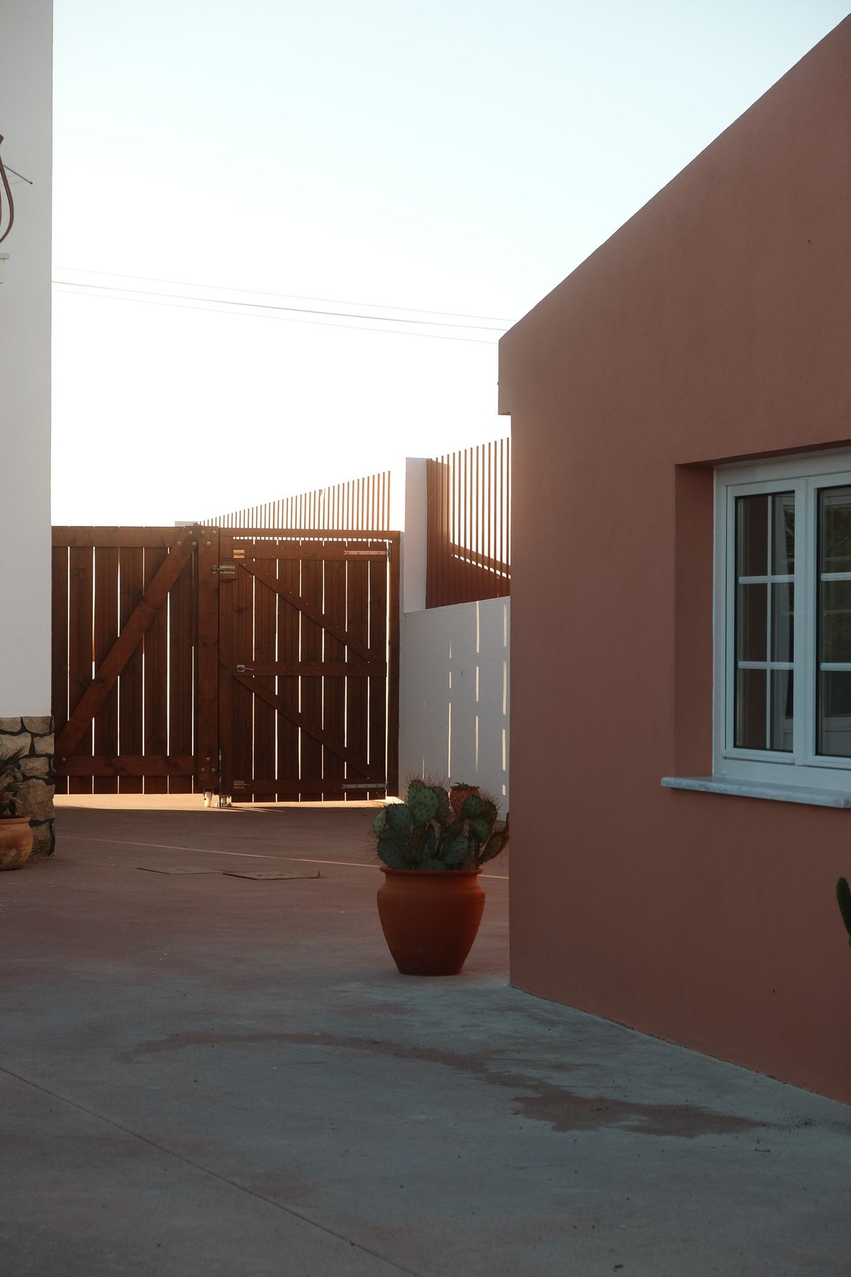 Terracotta house wall and wooden gate in evening light
