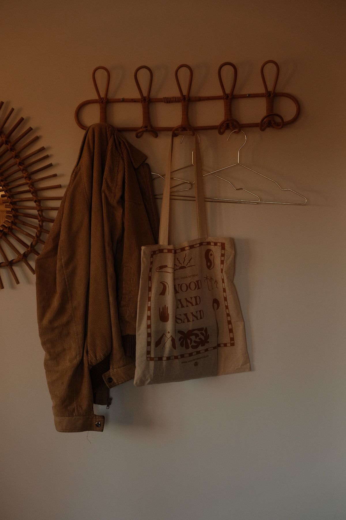 Jacket and Wood and Sand tote bag on a rattan coat hook