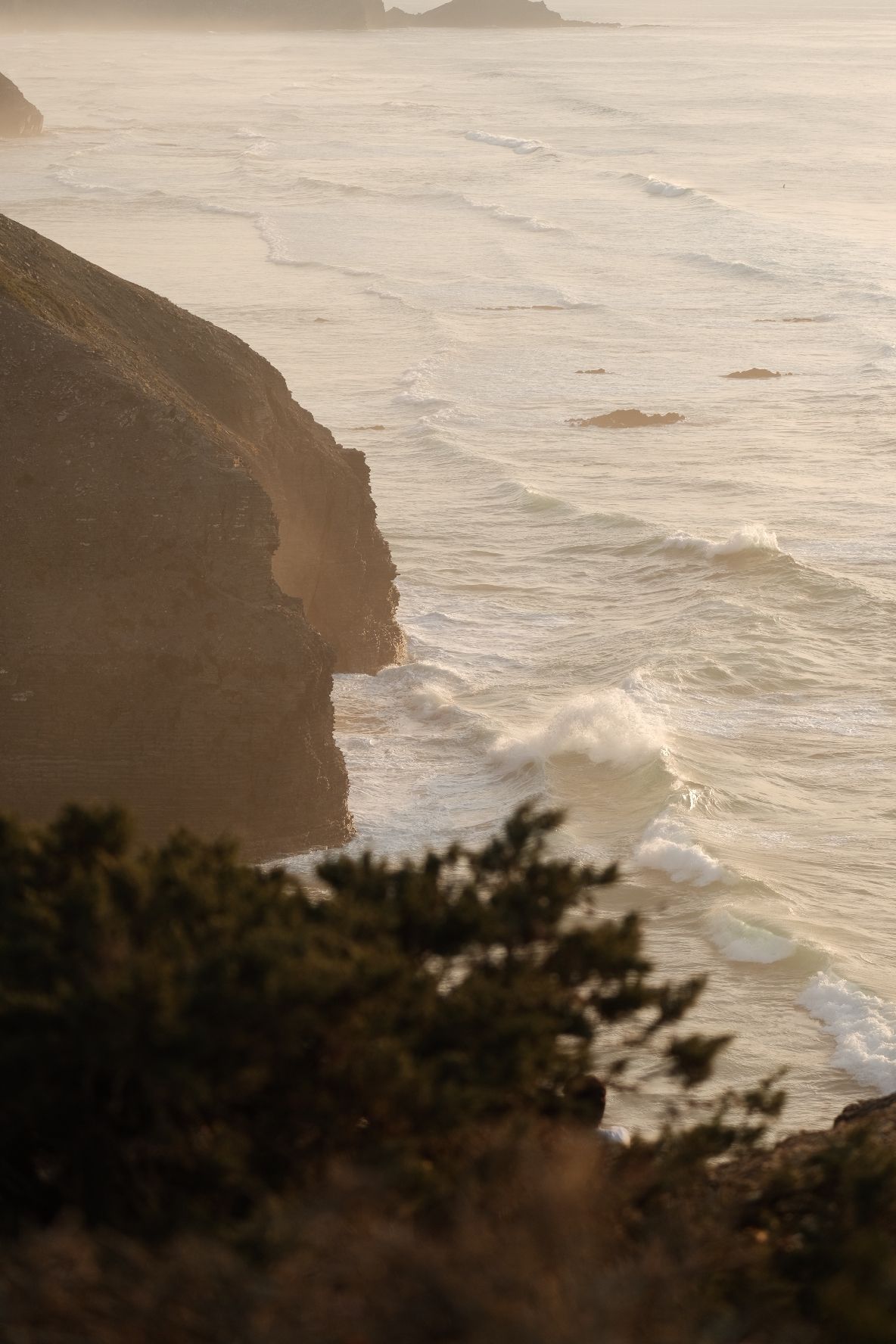 Cliff and breaking waves in warm evening light