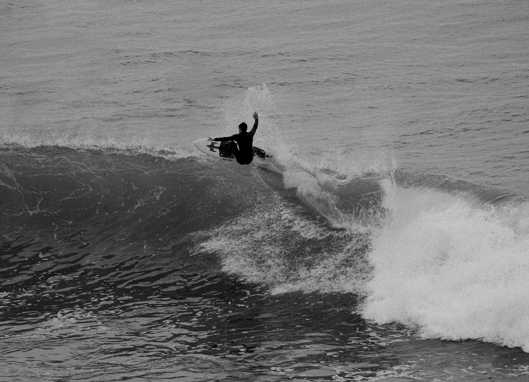 Black and white shot of a surfer hitting the lip of a wave