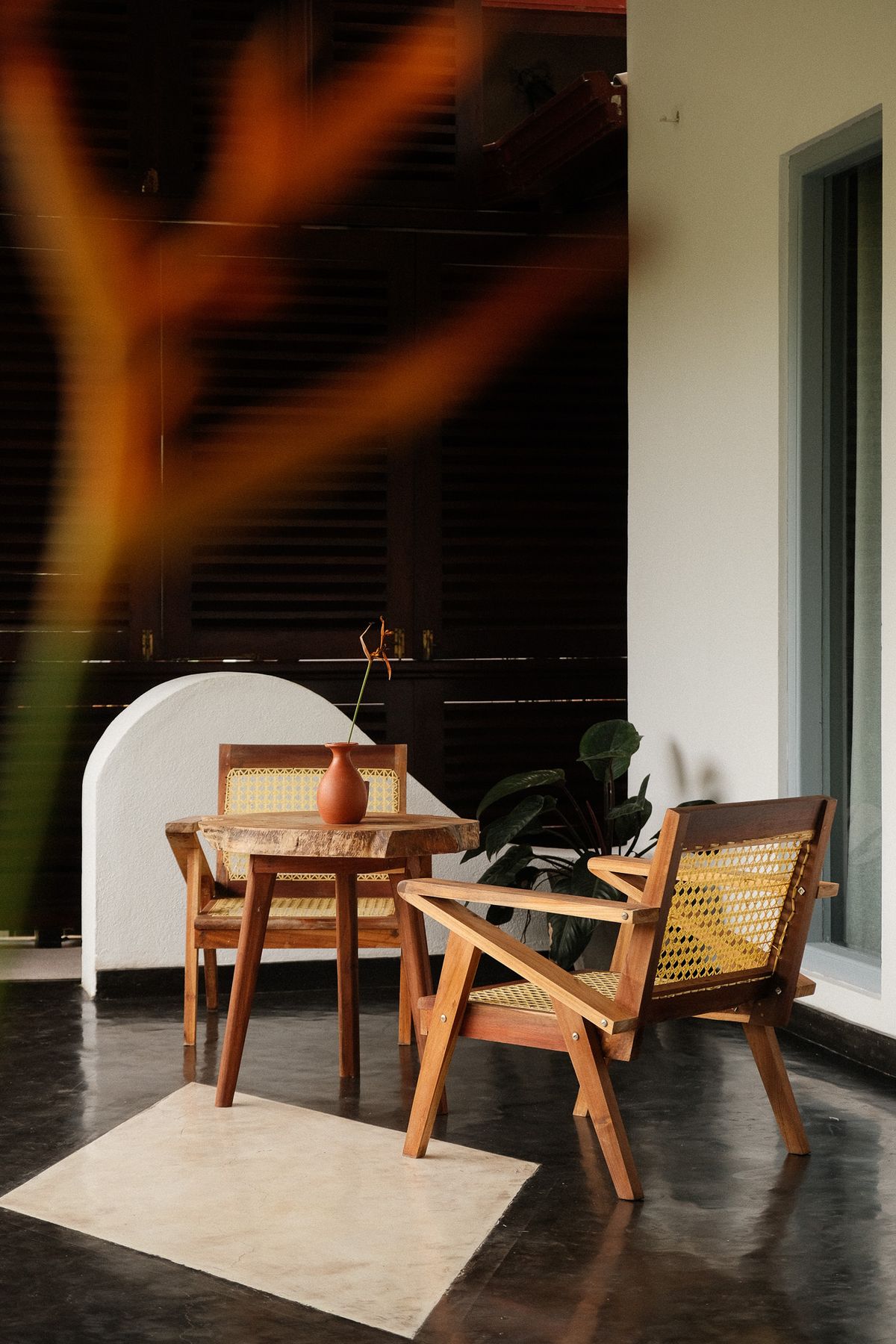 Teak table and chairs on a villa terrace, orange flower in the foreground