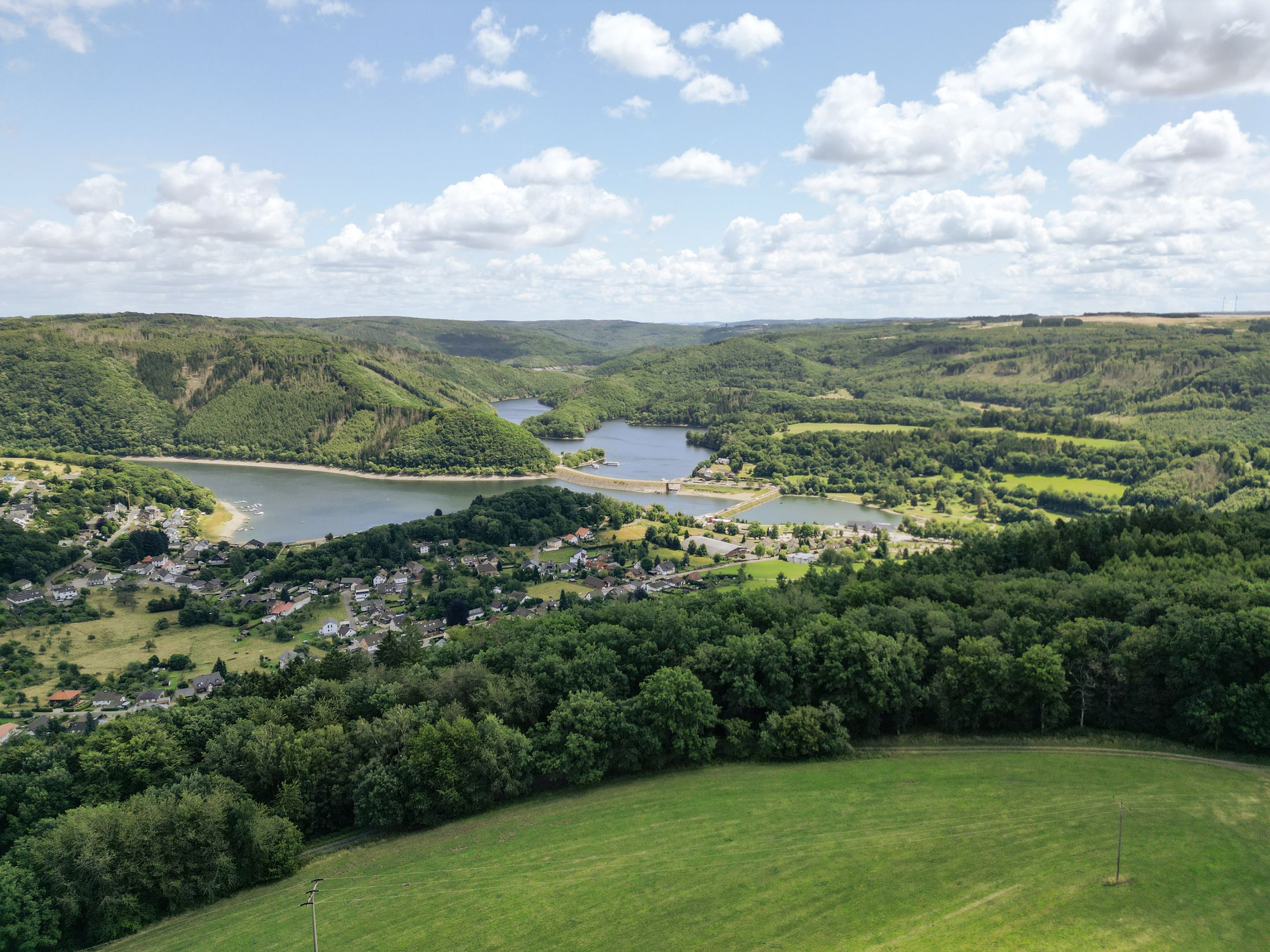View from above over a green valley with a lake and a village